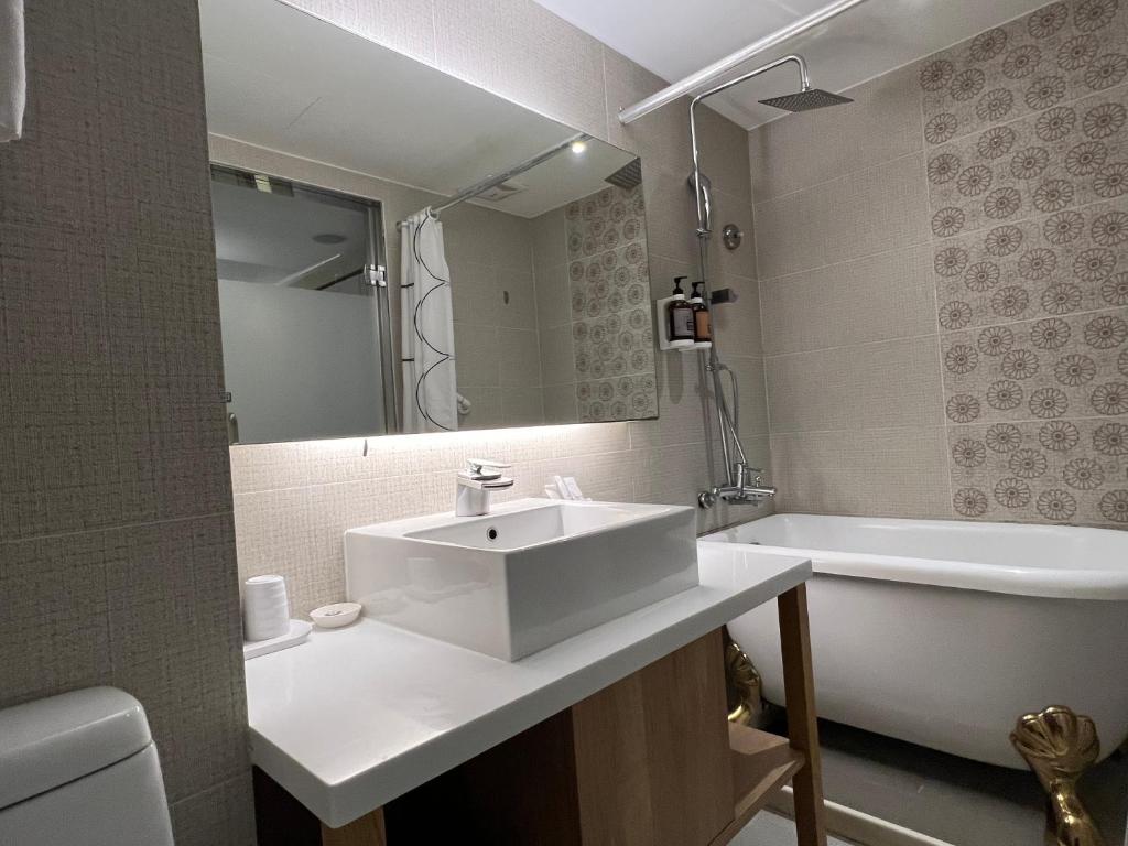 a bathroom with a sink and a bath tub and a sink at 台北馥華商旅 松江館 in Taipei