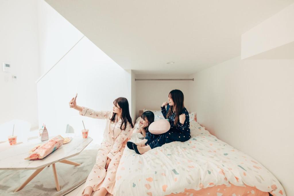 un gruppo di tre ragazze sedute su un letto di YOUR ROOM Kumamoto Sta little 203 Vacation STAY 75726 a Kumamoto