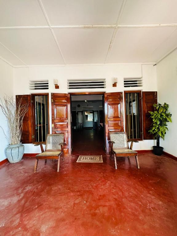 een lege kamer met 2 stoelen en een rode vloer bij Villa Gihan in Hikkaduwa