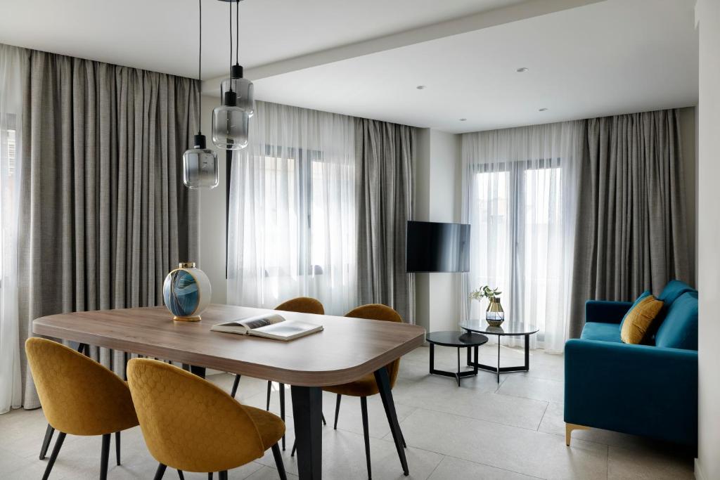 a living room with a dining room table and a blue couch at Hestia - Kolokotroni 23 in Athens