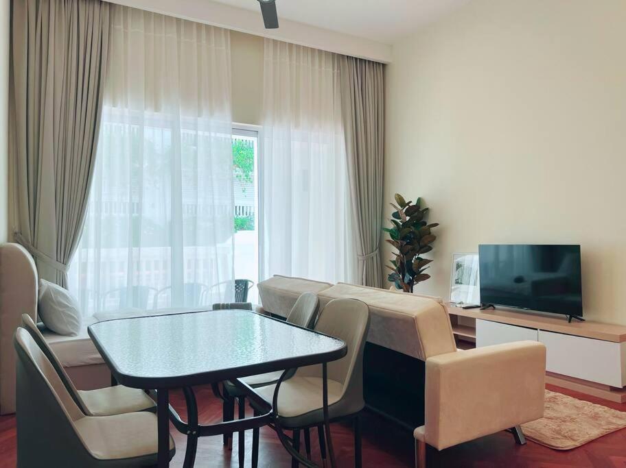 een woonkamer met een tafel en stoelen en een televisie bij Strait Quay Marina Cozy Suite with Bathtub by Uptrend Home Management in Tanjong Tokong