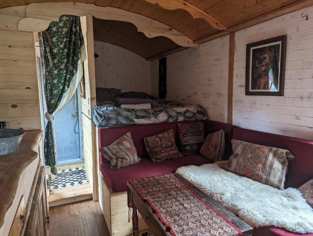 um quarto com um sofá e duas camas num camarote em roulotte à la mauvaise herbe em Barjols