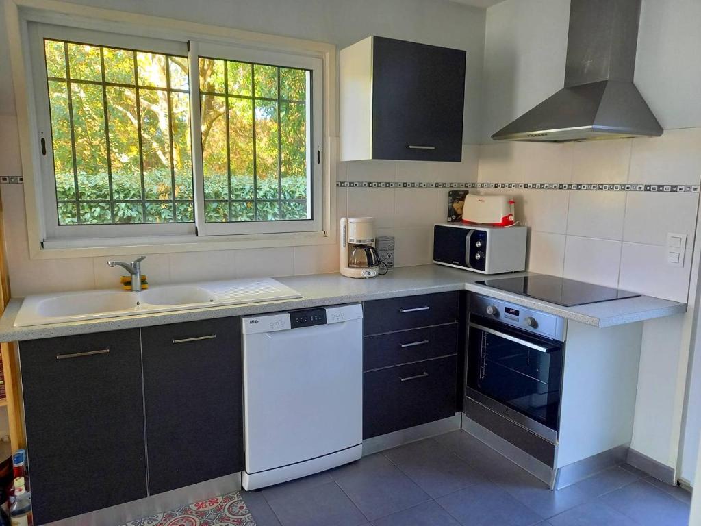 une petite cuisine avec un évier et une cuisinière dans l'établissement CAPBRETON -Appartement rez de jardin quartier proche centre et plages 5 pers, à Capbreton