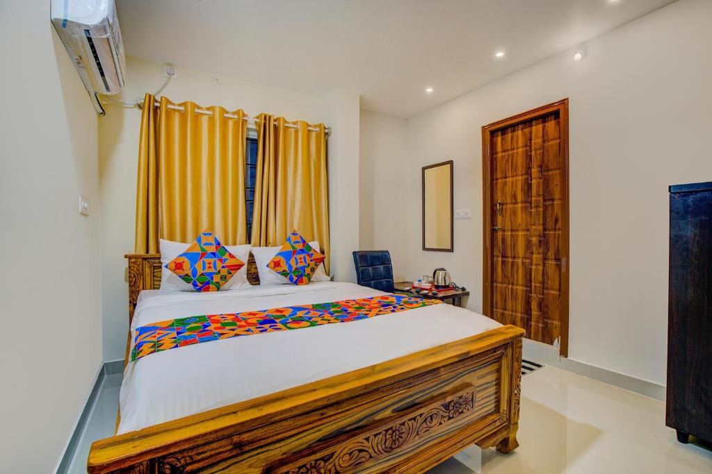 a bedroom with a large bed with yellow curtains at FabExpress Rithun Residency in Bangalore