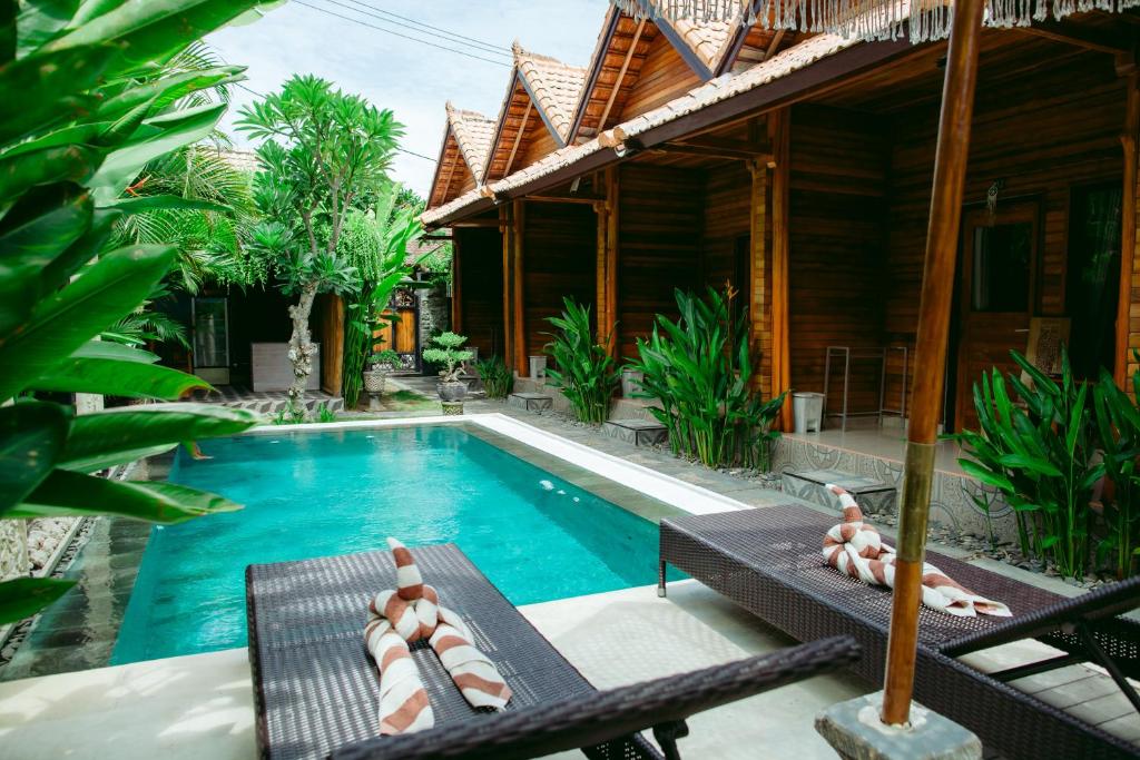 una piscina con sedie a sdraio e una casa di Kinton Guesthouse a Nusa Penida