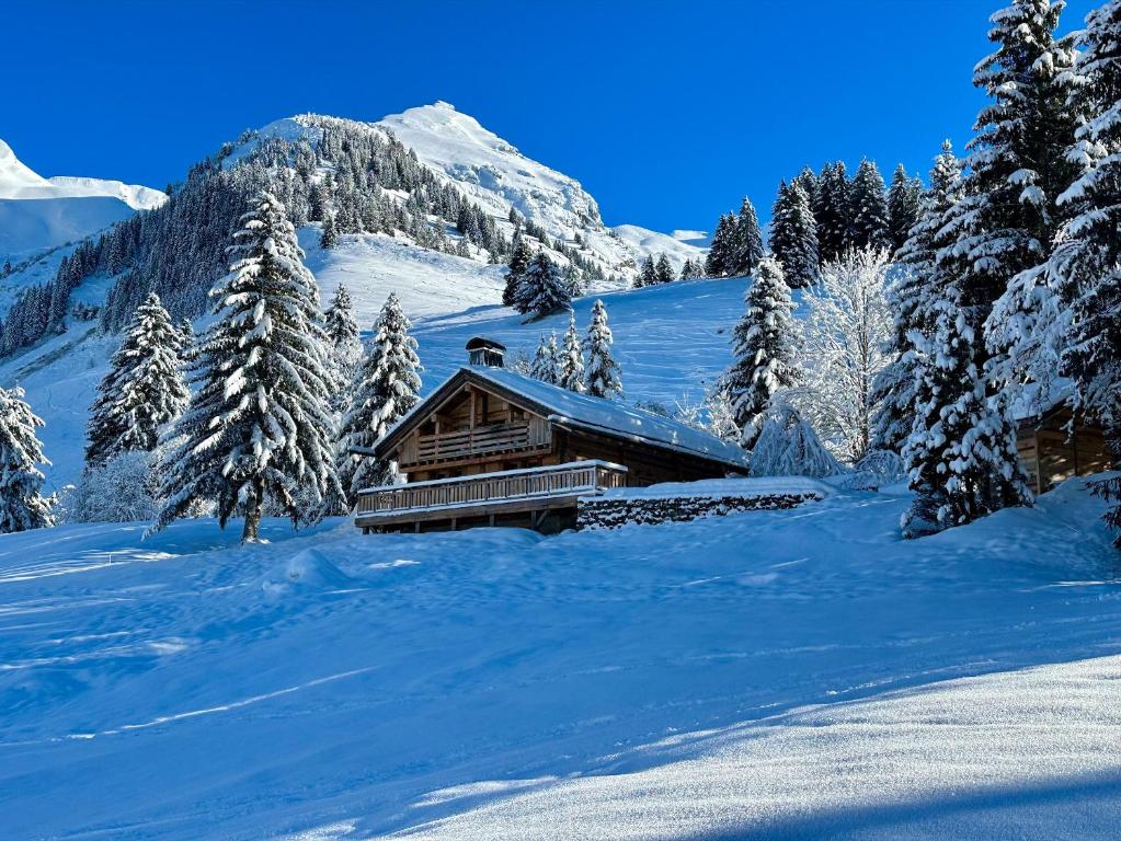 a log cabin in the snow with snow covered trees at SmartStay - Chalet Felix aux Confins in La Clusaz
