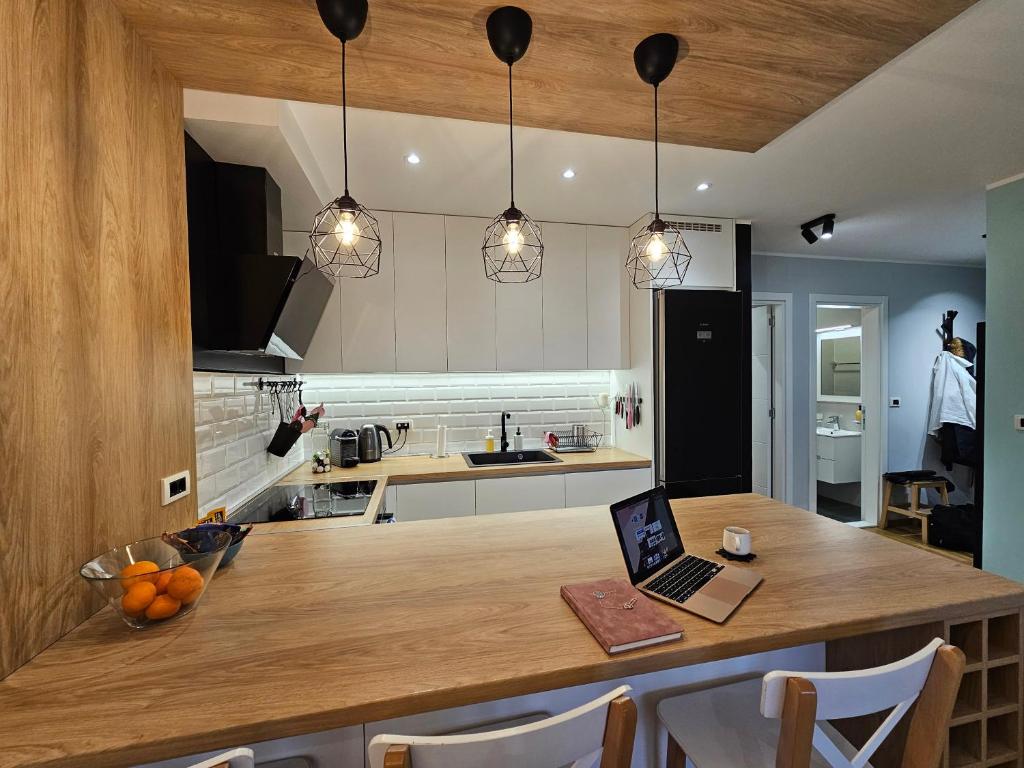 Turquoise Apartment (Private Garage) في نوفي ساد: مطبخ مع طاولة خشبية مع جهاز كمبيوتر محمول