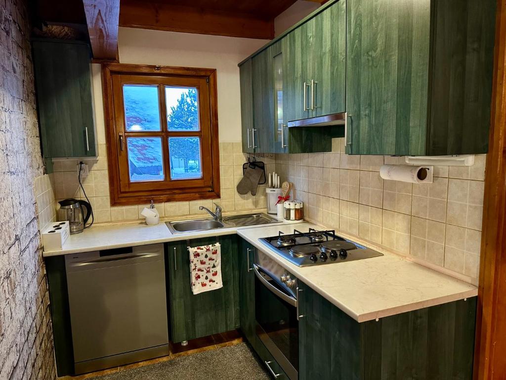 - une cuisine avec des placards verts, un évier et une cuisinière dans l'établissement Cozy House Blidinje, à Blidinje