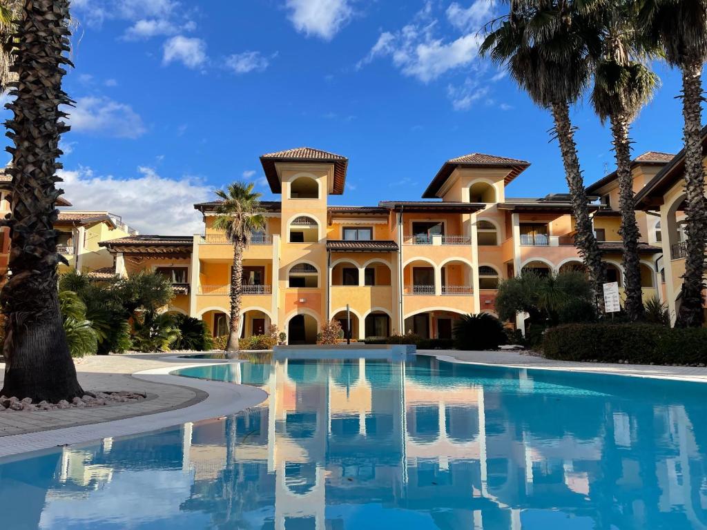 un gran edificio con palmeras y una piscina en Benaco Village Home, en Toscolano Maderno