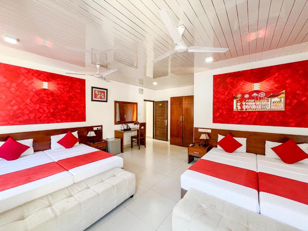 two beds in a room with red paintings on the walls at My City Hotel in Kandy