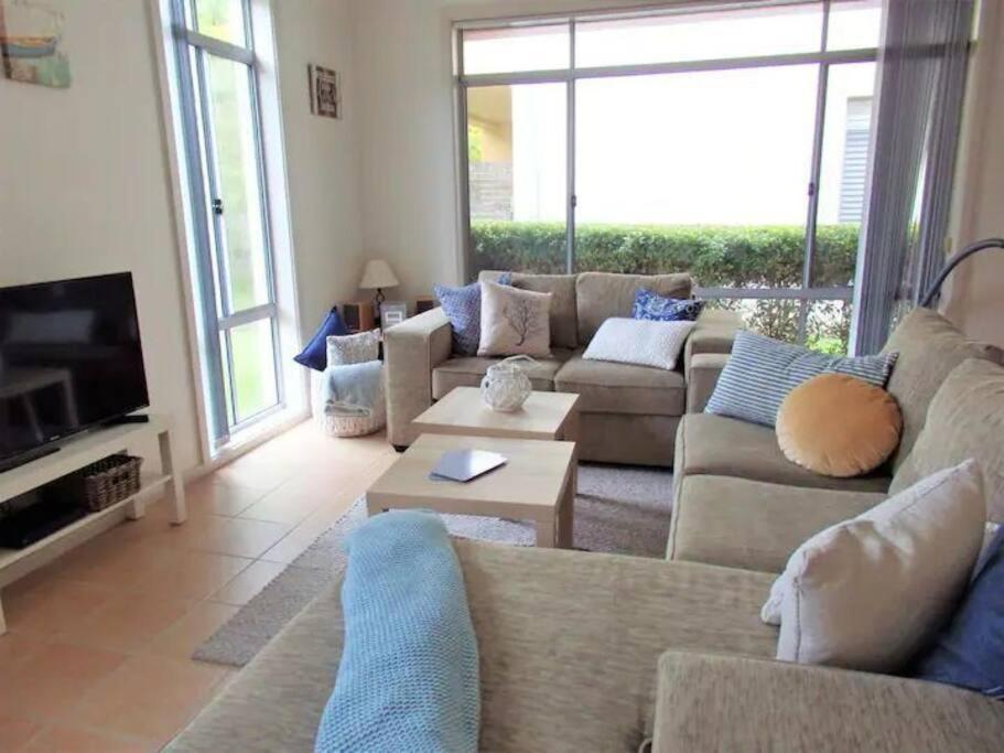 a living room with a couch and a tv at Bec's Beach House Getaway in Batemans Bay