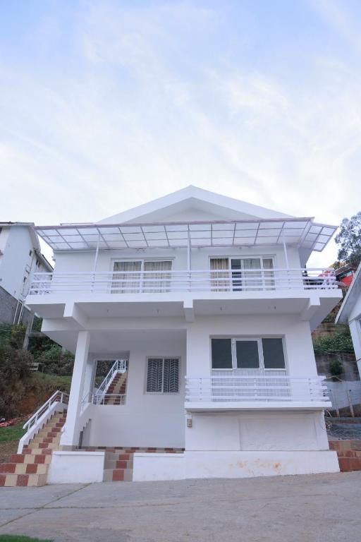 a white house with a balcony at Seven Endue Delight with Mountain view on the Hill Top in Ooty