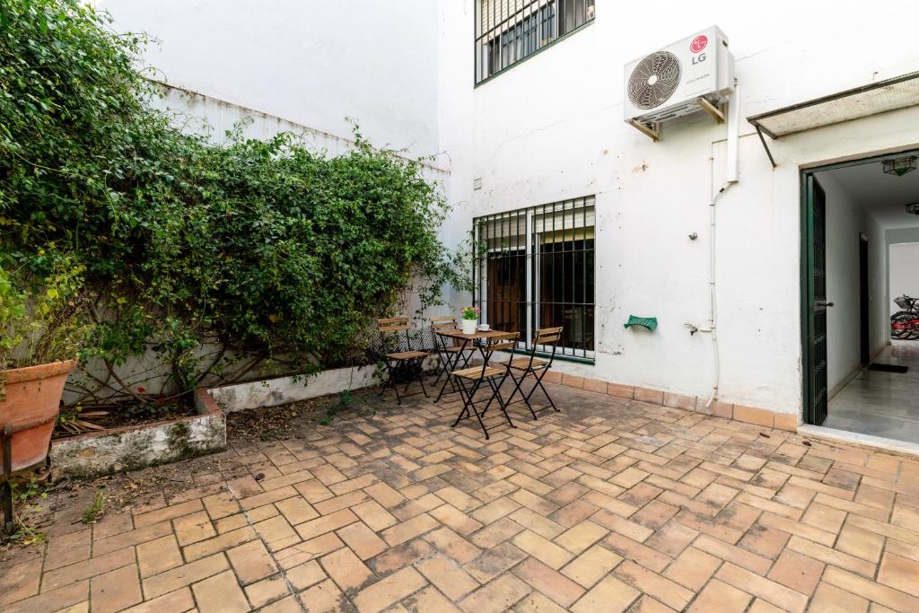 un patio con mesa y sillas junto a un edificio en Holi-Rent Esperanza, en Sevilla
