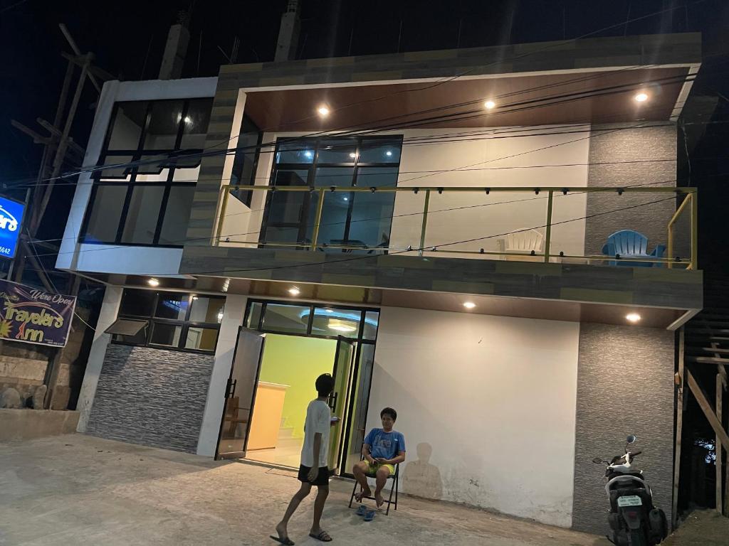 zwei Männer standen nachts vor einem Haus in der Unterkunft Dapitan Travellers Inn in Dapitan