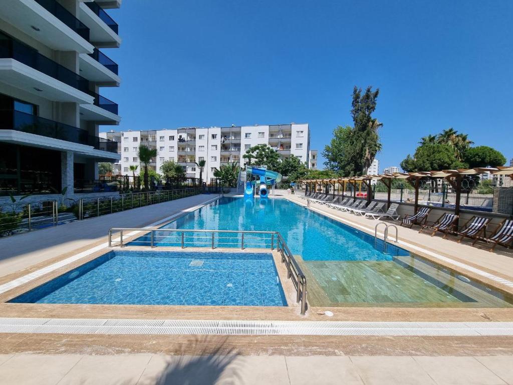 a large swimming pool with chairs and a building at Uğur Apart Sea View Premium in Mersin