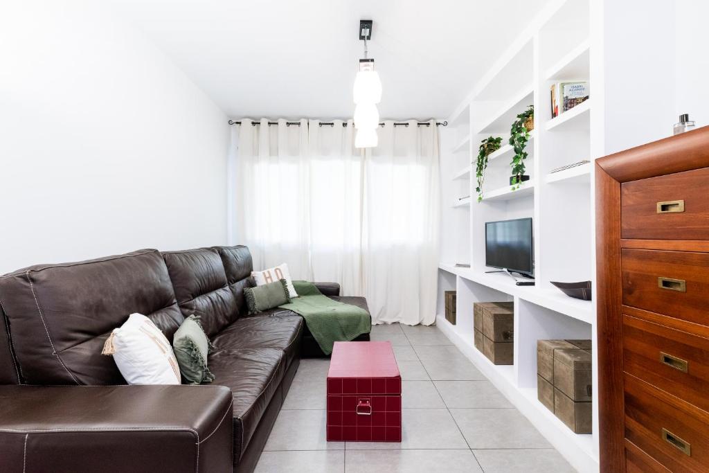 sala de estar con sofá de cuero marrón y TV en tuGuest Avenida de la Investigación - Free parking, en Granada