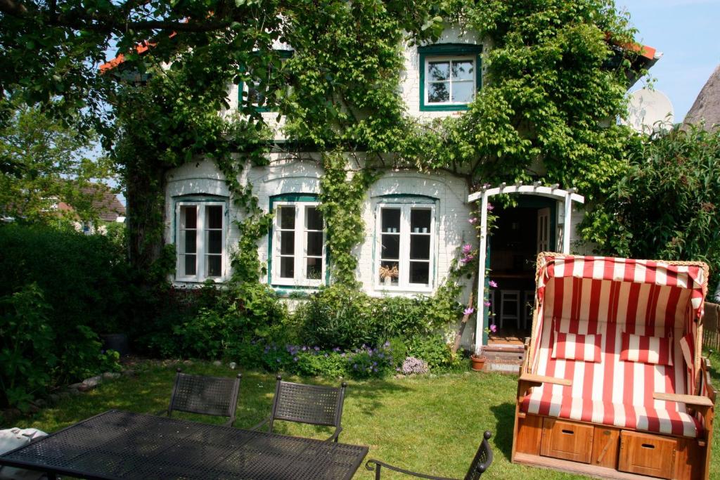 uma cadeira vermelha e branca em frente a uma casa em "Weißes Haus" 9123II - Fehmarn em Fehmarn