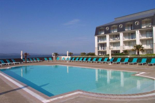 uma grande piscina em frente a um hotel em Appartement face Mer em Tréboul