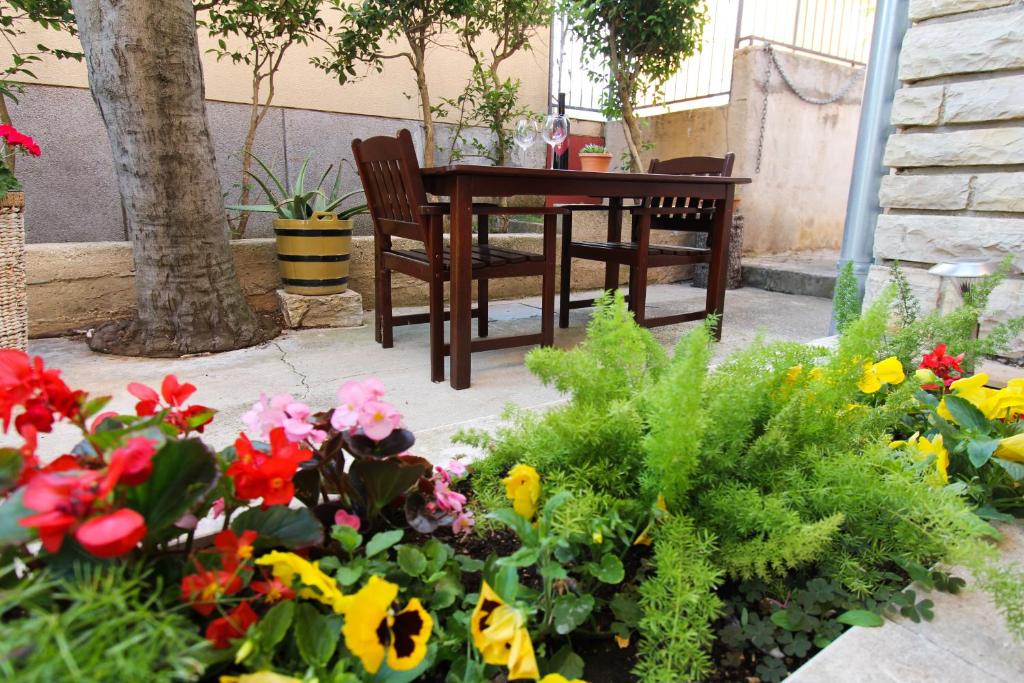 a table and chairs in a garden with flowers at Apartmani Roje Sveti Filip I Jakov in Sveti Filip i Jakov