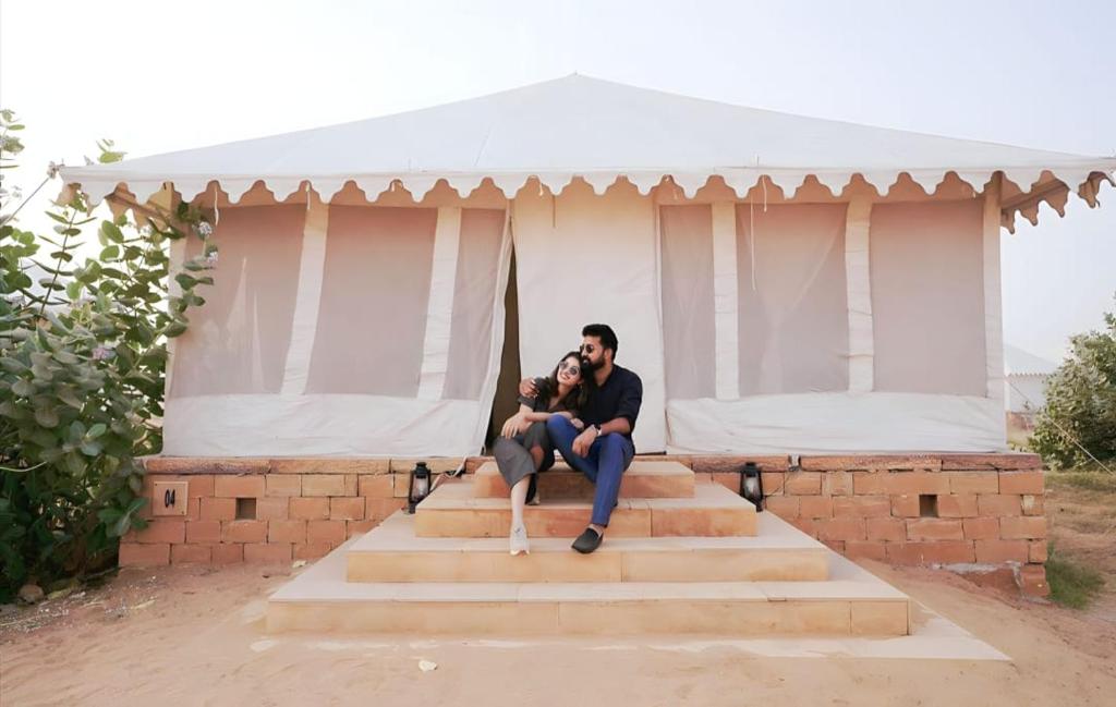 un hombre y una mujer sentados en escalones bajo una tienda en The Heritage Luxurious Camp en Jaisalmer
