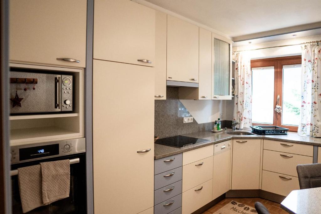 a kitchen with white cabinets and a microwave at Appartement Mountainrelax Gastein in Dorfgastein