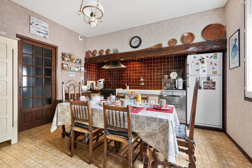 a kitchen with a table with chairs and a refrigerator at Au Nid de la Madeleine in Gaillac