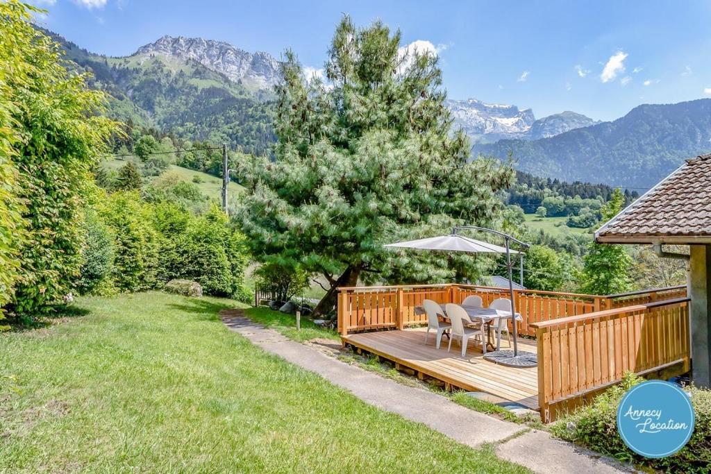 a wooden deck with chairs and an umbrella at The Bergerie T3- View Mountains in La Pirraz