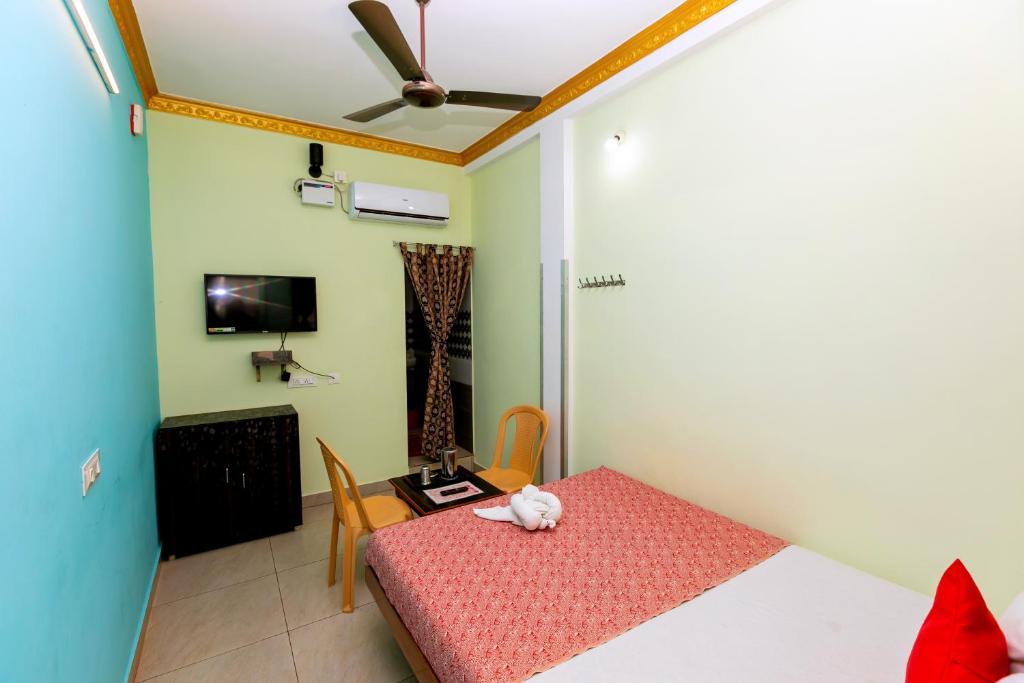 a room with a bed and a table and a tv at PRIMES RESIDENCY in Kālapettai