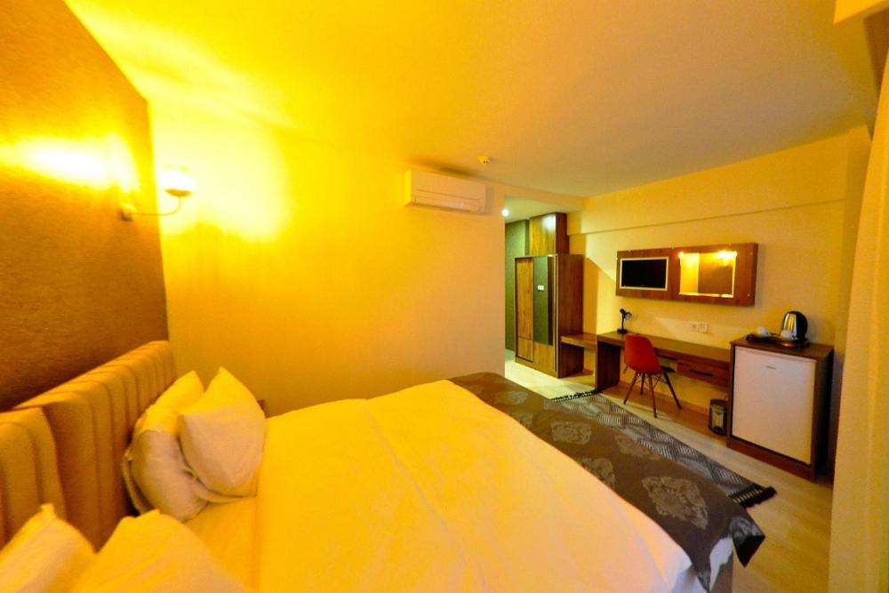 een hotelkamer met een bed met een gele muur bij La Boutique Atlantik Hotel in Tekirdag