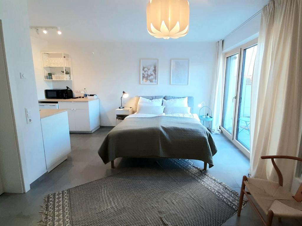 a white bedroom with a bed and a kitchen at Bude 23 - Ferienwohnung Aalen in Aalen
