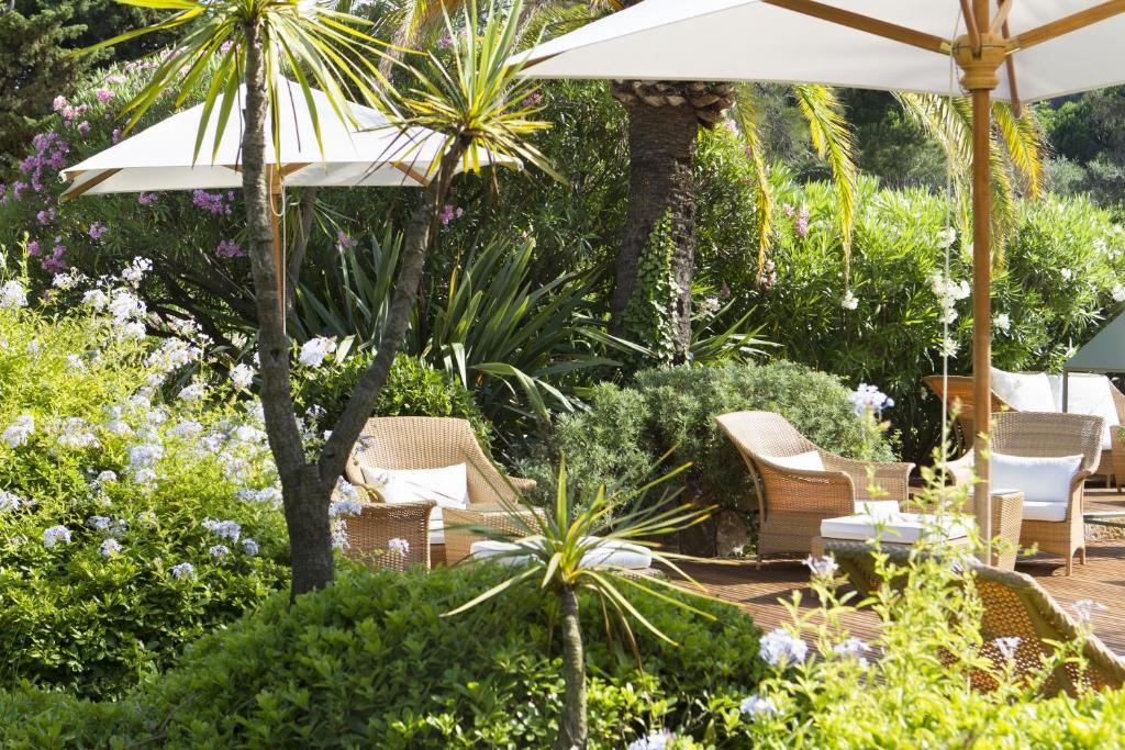 a patio with chairs and umbrellas in a garden at Hotel Royal-Riviera in Saint-Jean-Cap-Ferrat