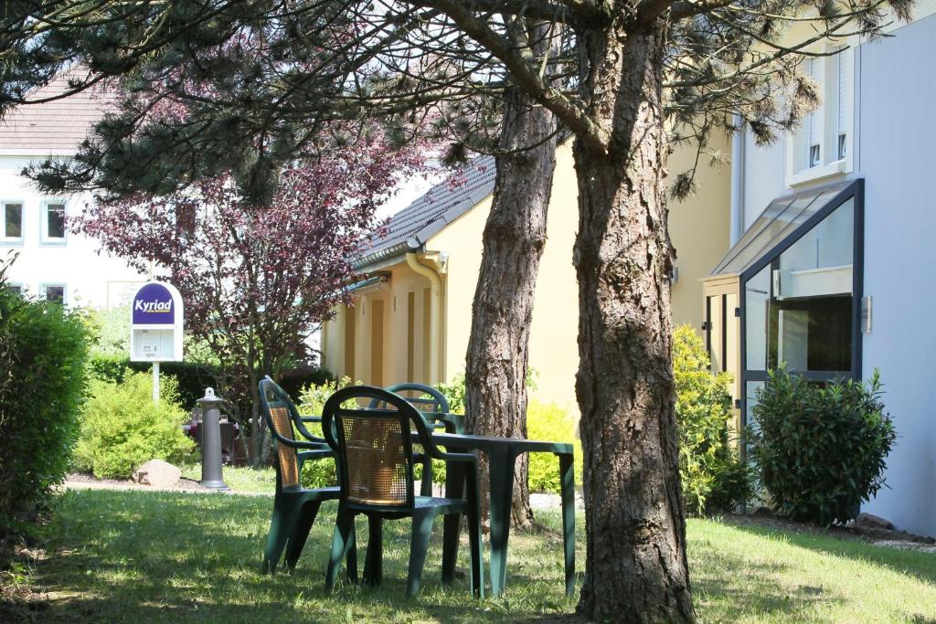 a group of chairs sitting next to a tree at Kyriad Nancy Sud - Ludres in Ludres