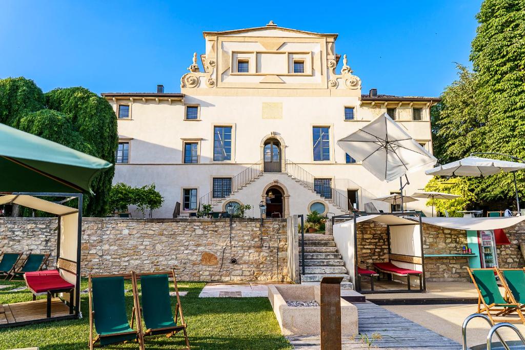 um edifício com cadeiras e guarda-sóis em frente em Villa Balis Crema Verona Hills em Grezzana