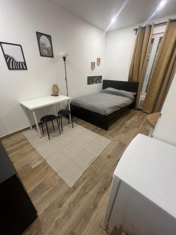 - une chambre avec un lit, un bureau et une table dans l'établissement studio neuf rue de saint denis (colombes), à Colombes