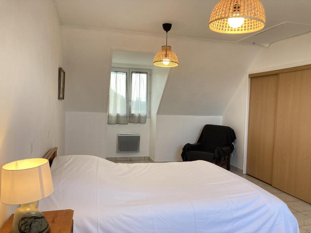 a bedroom with a white bed and a chair at LE COQ - Maison 10 personnes - Locmariaquer in Locmariaquer