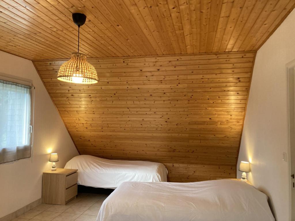 two beds in a room with a wooden ceiling at LE COQ - Maison 10 personnes - Locmariaquer in Locmariaquer