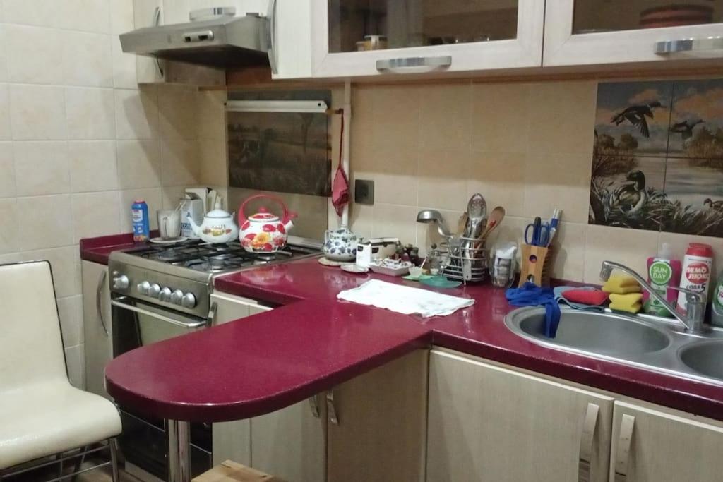 uma cozinha com um balcão vermelho e um lavatório em Квартира в Баку в тихом дворе em Baku