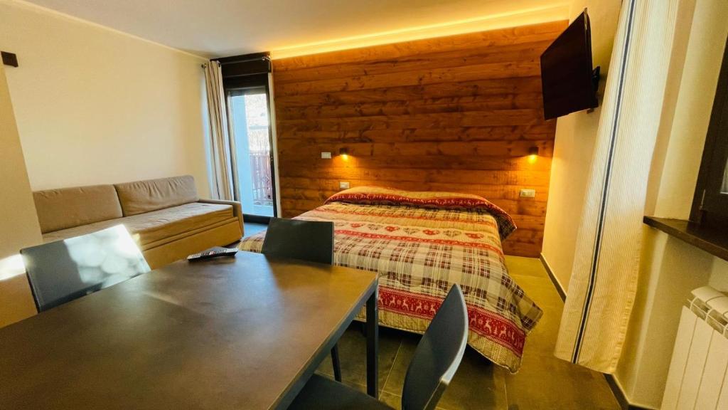 1 dormitorio con cama, mesa y sofá en Residence Villa Linda, en Bardonecchia