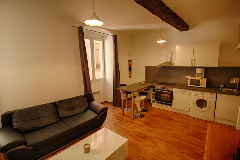 a living room with a couch and a kitchen at Studio Conventionnel Chiappe Vieille ville Ajaccio in Ajaccio