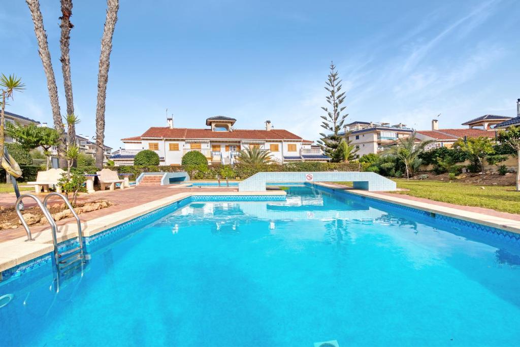 a large blue swimming pool with a house in the background at Parque Mar V in La Mata