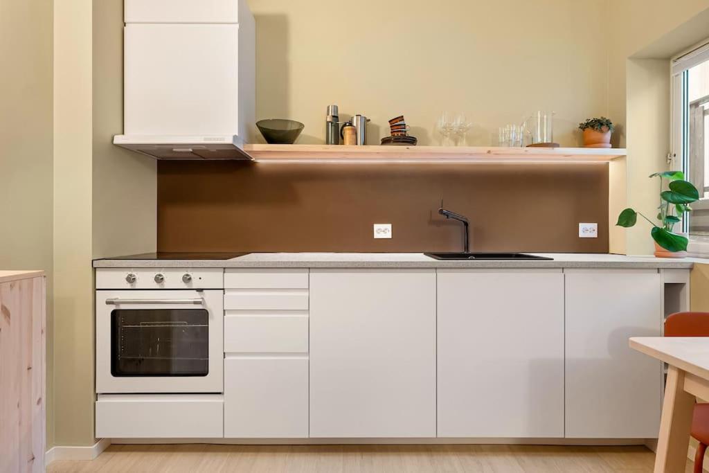 a kitchen with white cabinets and a sink at Fresh studio apartment, a short walk from Bryggen in Bergen