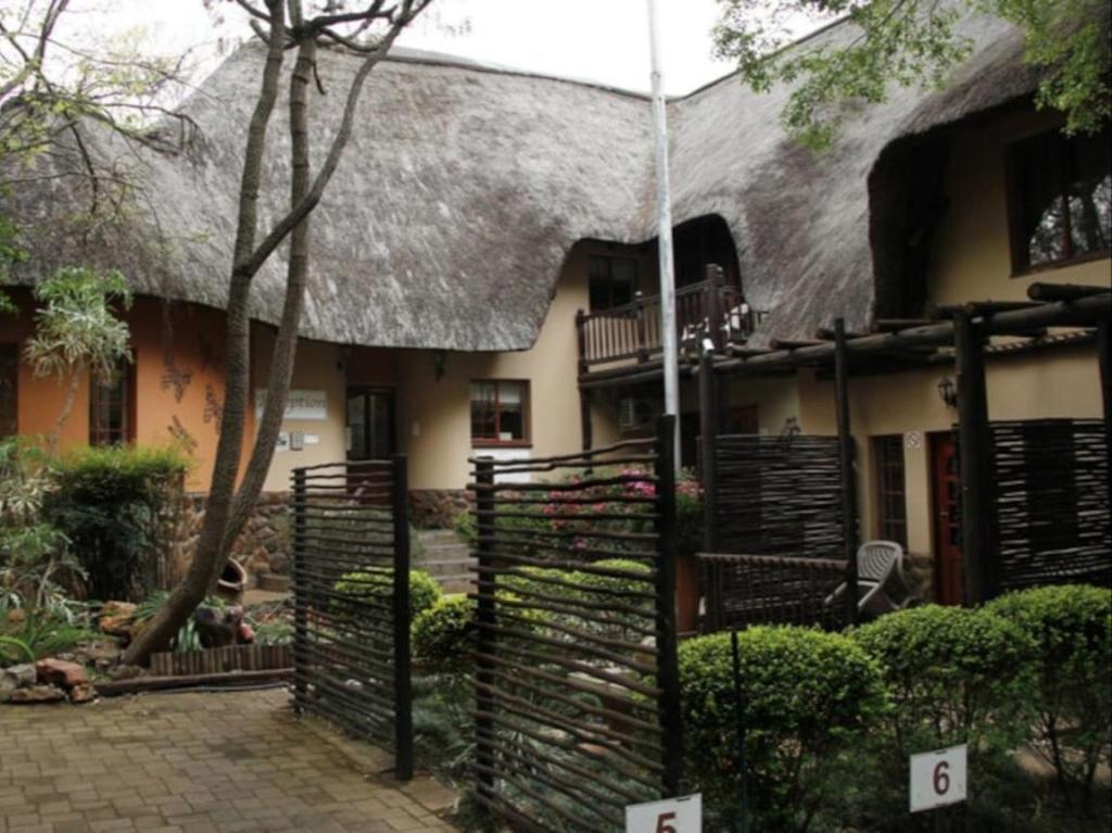 a house with a thatched roof and a fence at Lapalosa Lodge in Centurion