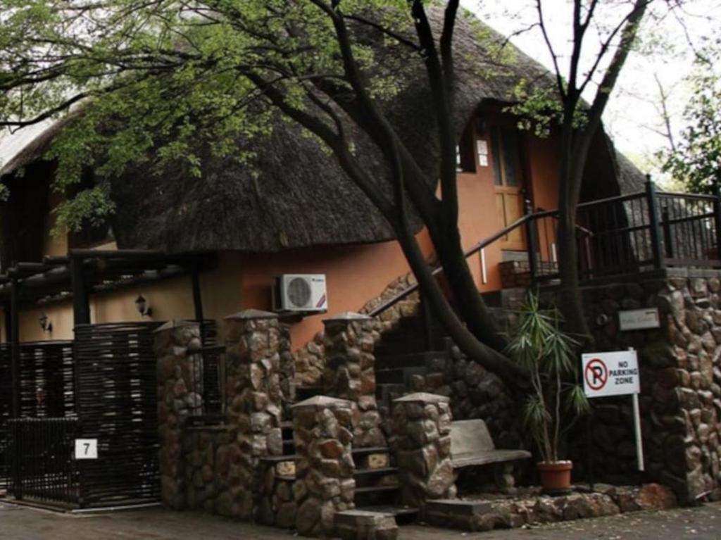 a house with a thatch roof and a stone wall at Lapalosa Lodge in Centurion