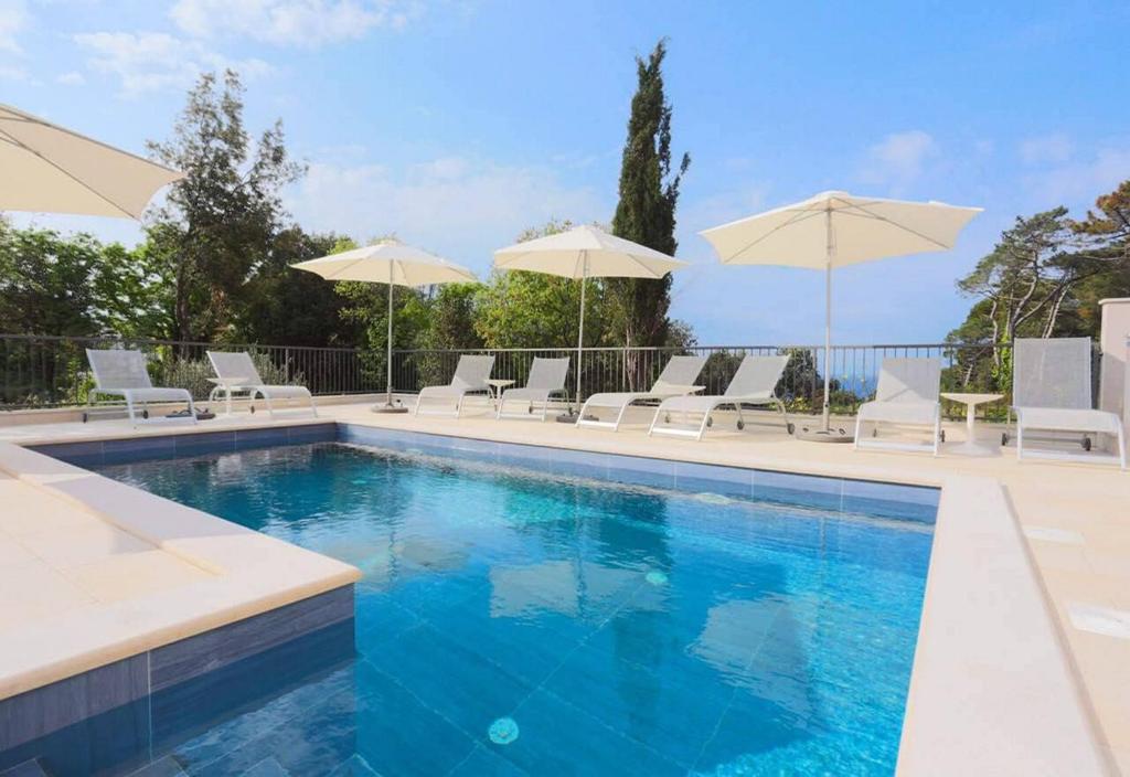 uma piscina com cadeiras e guarda-sóis em Apartments Villa Lukas em Cavtat