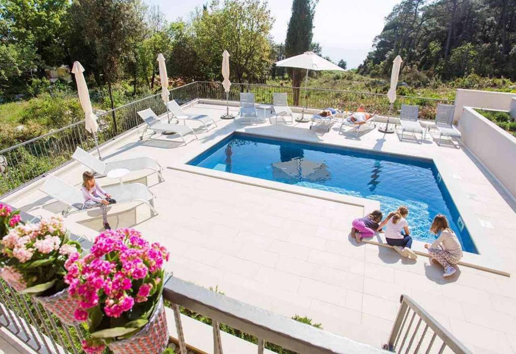 un grupo de personas sentadas alrededor de una piscina en Apartments Villa Lukas, en Cavtat
