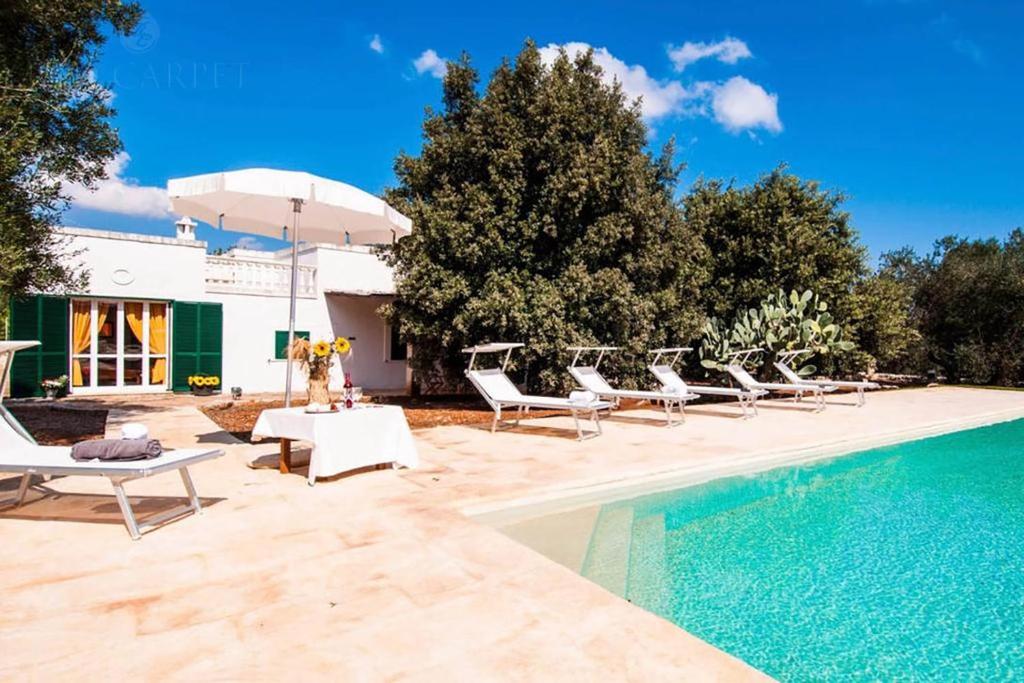 einen Pool mit Liegestühlen und einem Sonnenschirm neben einem Pool in der Unterkunft Masseria Terramare in Macchia di Monte