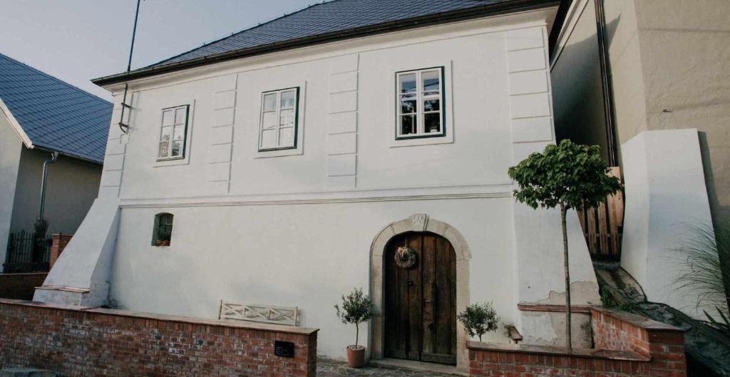 a small white house with a door and a tree at Vinařský dům Mařatice in Uherské Hradiště