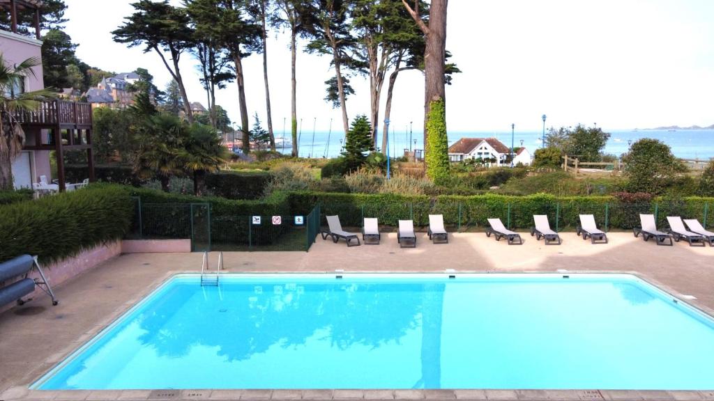 une grande piscine avec des chaises longues dans l'établissement Appartement avec PISCINE, plage de Trestraou à PERROS-GUIREC - Réf 505, à Perros-Guirec