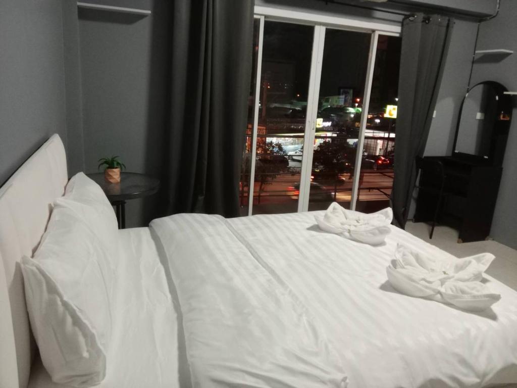 a white bed in a room with a window at Grand Bangsaen Hotel in Bangsaen