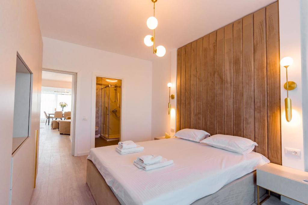 ein Schlafzimmer mit einem großen weißen Bett mit einem hölzernen Kopfteil in der Unterkunft WAVE 4 Apartments Mamaia Nord in Năvodari